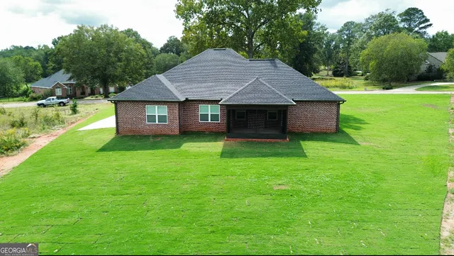 a aerial view of a house next to a yard and brick wall
