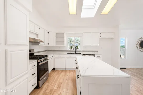 a kitchen with granite countertop a sink a stove and refrigerator
