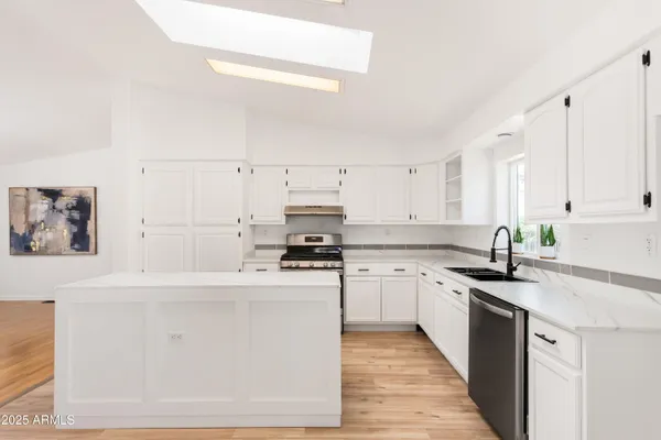 a kitchen with stainless steel appliances granite countertop a stove top oven a sink a stove and white cabinets