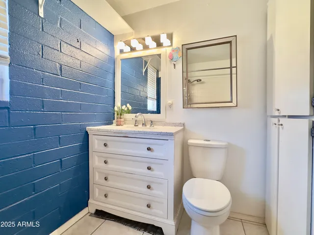 a bathroom with a granite countertop toilet sink and mirror