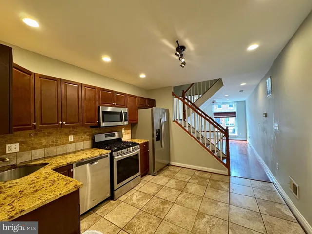 a kitchen with stainless steel appliances granite countertop a stove refrigerator and a sink