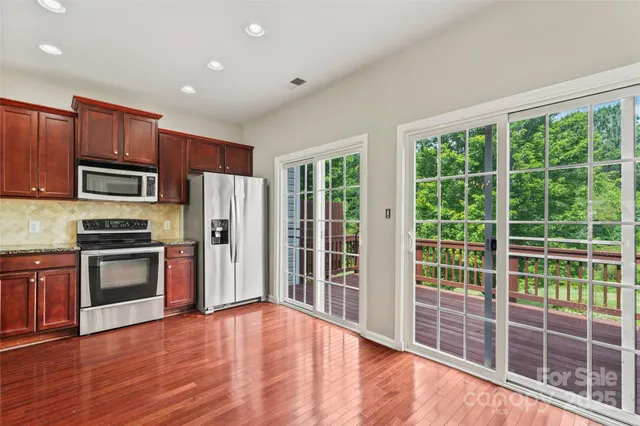a view of kitchen with stainless steel appliances granite countertop a refrigerator and a stove top oven