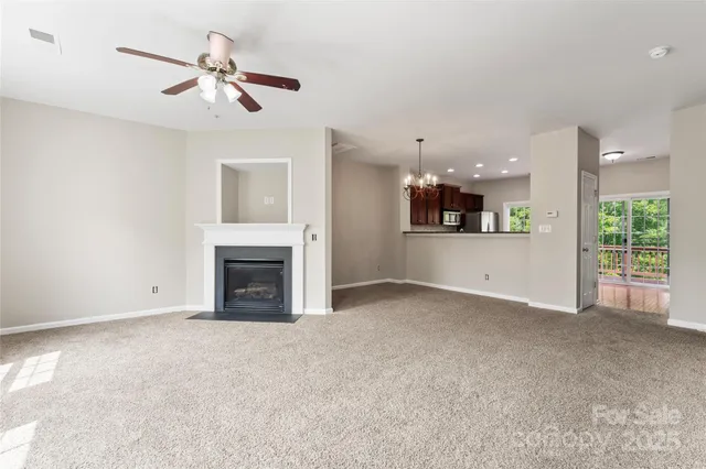 a view of a livingroom with a fireplace a ceiling fan and windows