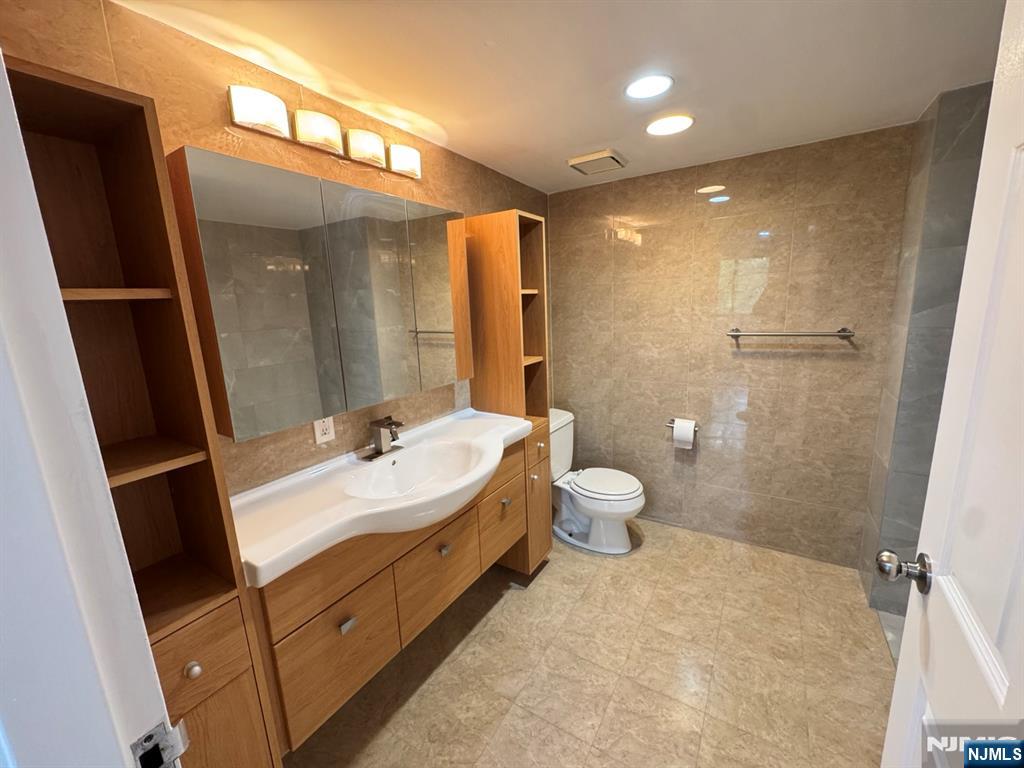 55 Clinton Place, Unit 502 Hackensack, NJ 07601 - Photo 13 of 18 a spacious bathroom with a double vanity sink toilet mirror and shower