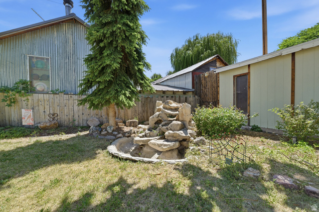365 North Main Street Fillmore, UT 84631 - Photo 9 of 51 Expansive backyard featuring a stone water feature, mature evergreen tree, and a wooden privacy fence
