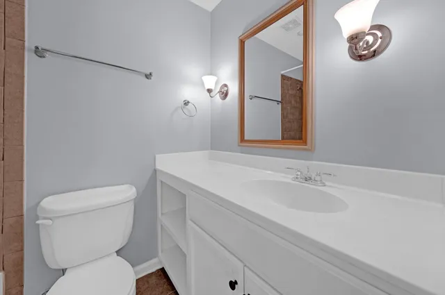 a bathroom with a toilet sink vanity and mirror