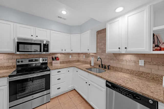 a kitchen with granite countertop white cabinets and stainless steel appliances
