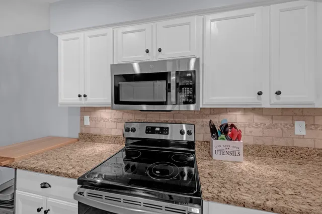 a kitchen with stainless steel appliances granite countertop white cabinets and a stove a oven with white countertops