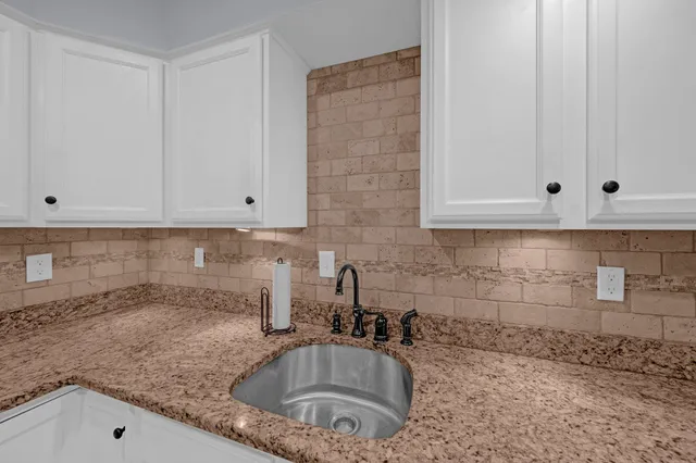 a kitchen with granite countertop white cabinets and a sink