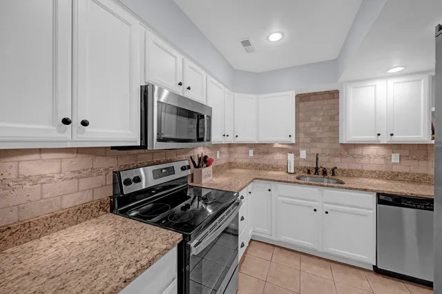 a kitchen with granite countertop a sink stove and microwave