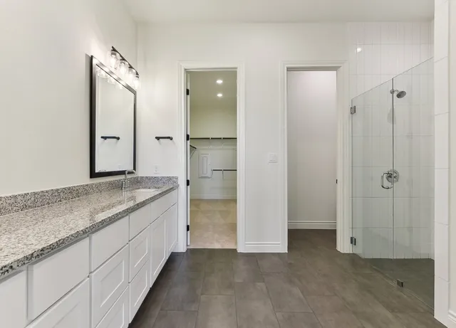 a bathroom with a granite countertop sink mirror and shower