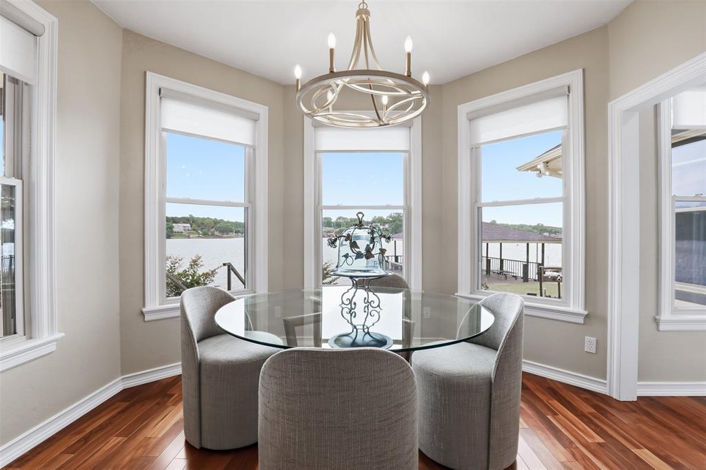 2406 River Road Granbury, TX 76048 - Photo 14 of 40 Dining area featuring a bay window with water views, wood-finish flooring, and a contemporary chandelier