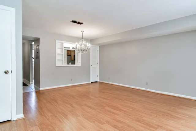 an empty room with wooden floor and chandelier