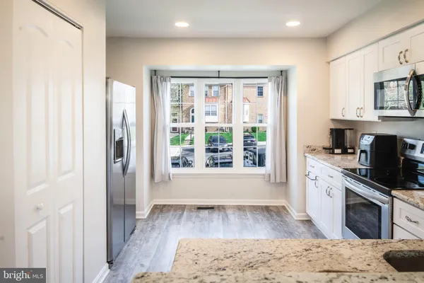 a kitchen with granite countertop white cabinets sink and stainless steel appliances
