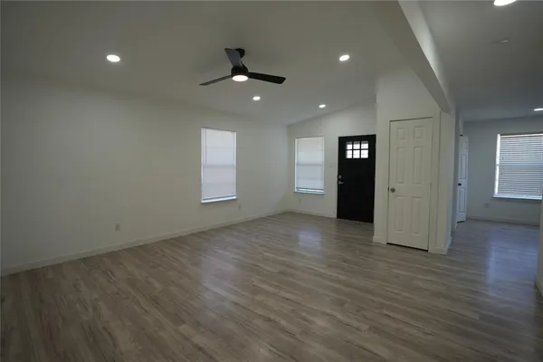 an empty room with wooden floor and windows