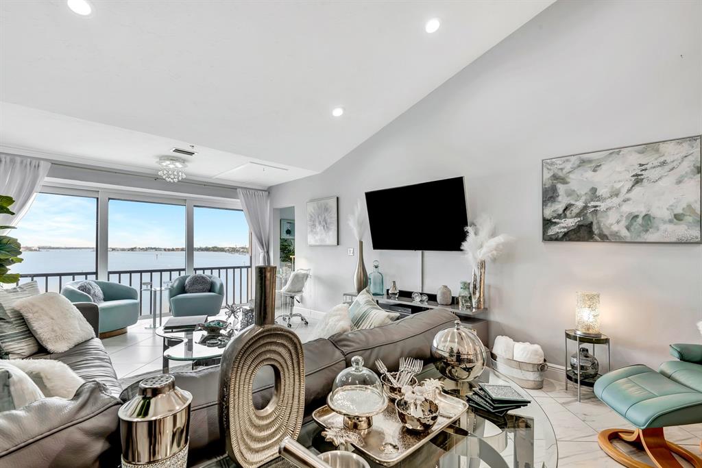 1602 Stickney Point Road, Unit 404 Sarasota, FL 34231 - Photo 16 of 38 a living room with furniture a flat screen tv and a floor to ceiling window