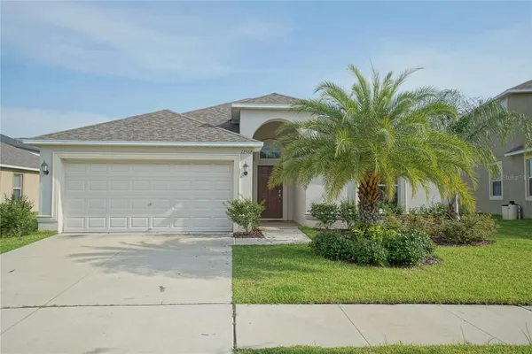 front view of house with a yard and palm trees