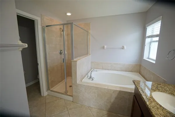a spacious bathroom with a granite countertop tub shower and mirror