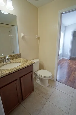 a spacious bathroom with a granite countertop toilet a sink and a mirror