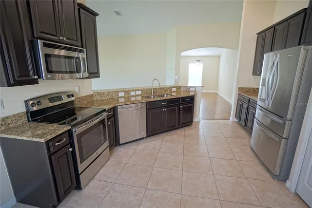 a kitchen with stainless steel appliances granite countertop a stove refrigerator and a sink