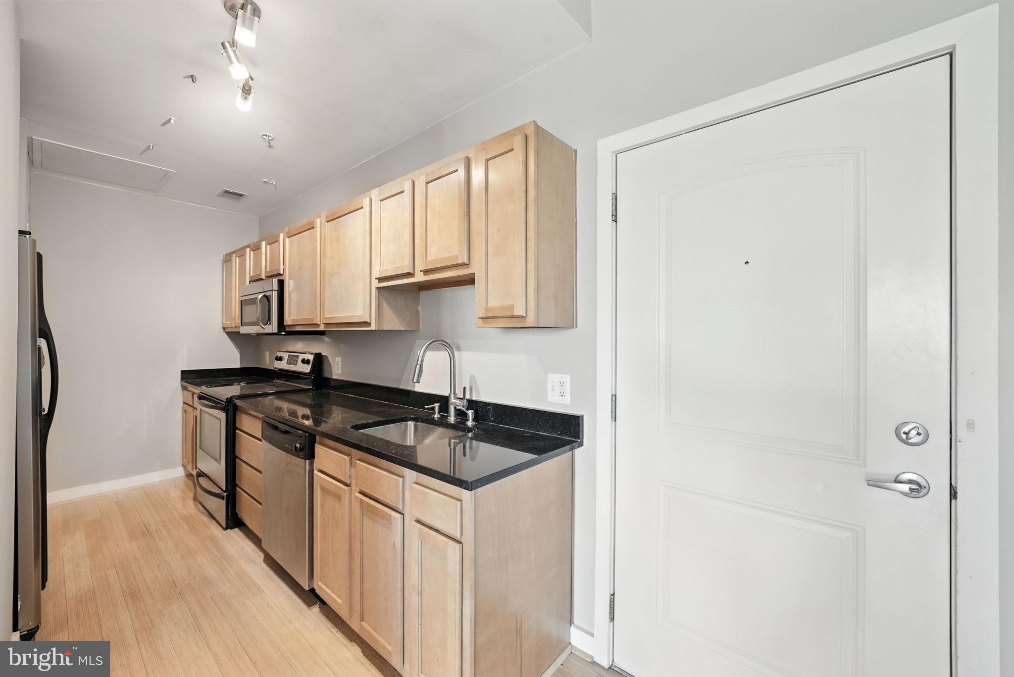 5885 Colorado Avenue Northwest, Unit 402 Washington, DC 20011 - Photo 14 of 30 a kitchen with stainless steel appliances granite countertop white cabinets stove a sink and dishwasher