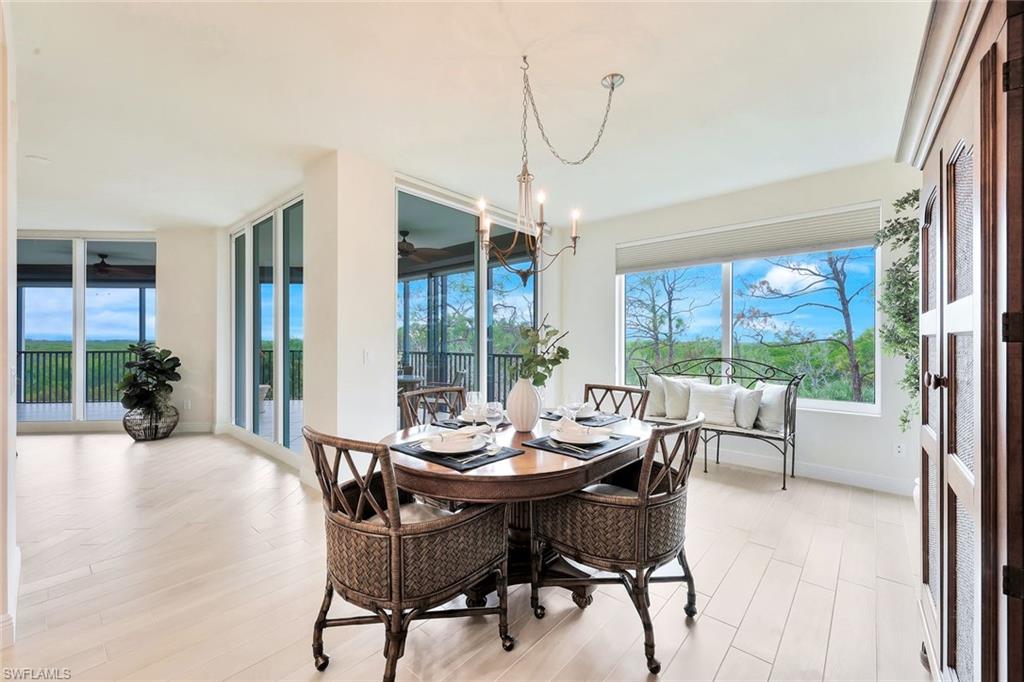 445 Cove Tower Drive, Unit 403 Naples, FL 34110 - Photo 11 of 42 a view of a dining room with furniture wooden floor and a chandelier