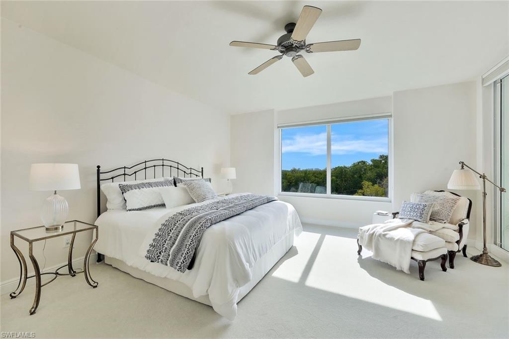 445 Cove Tower Drive, Unit 403 Naples, FL 34110 - Photo 12 of 42 a spacious bedroom with a bed a couch and a window