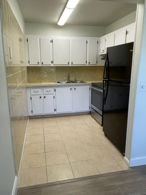 a kitchen with granite countertop a stove a refrigerator and cabinets