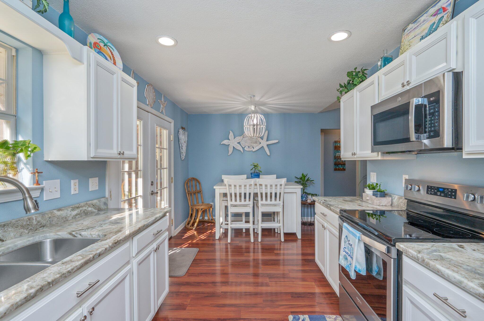 8933 Highway 90 Milton, FL 32583 - Photo 14 of 31 a kitchen with stainless steel appliances granite countertop a stove top oven a sink dishwasher a dining table and chairs with wooden floor