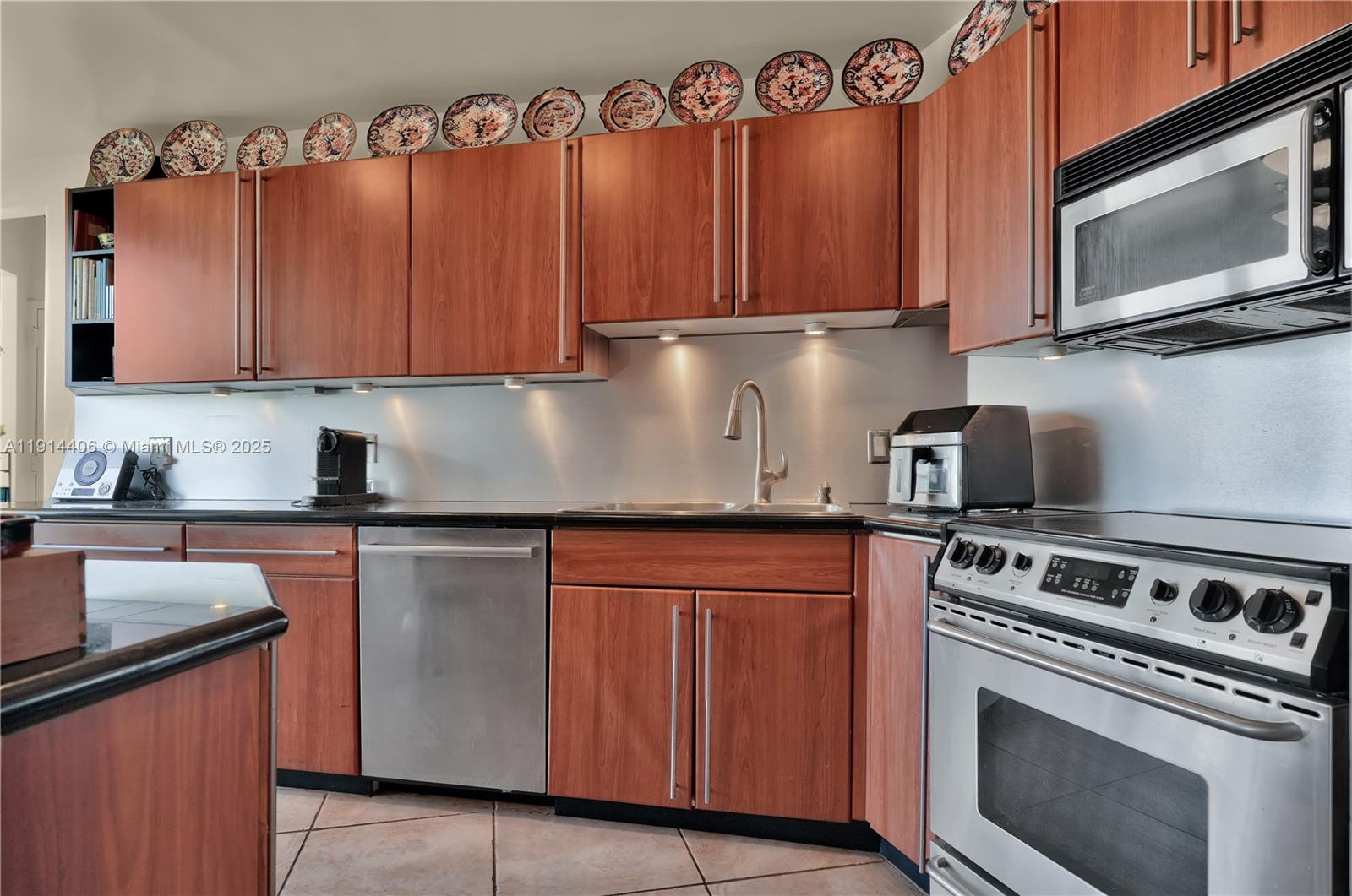 720 Northeast 69th Street, Unit 9W Miami, FL 33138 - Photo 13 of 27 a kitchen with granite countertop a stove top oven microwave and cabinets