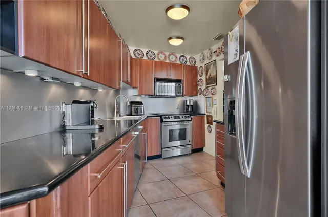 a kitchen with stainless steel appliances granite countertop a refrigerator a stove and a sink