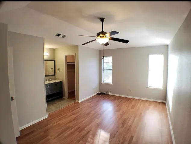 a view of empty room with wooden floor and fan
