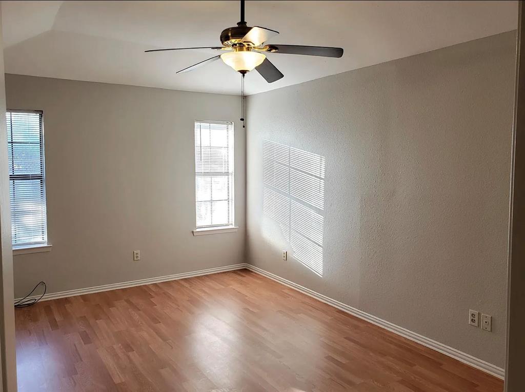 9693 Windy Ridge Road Frisco, TX 75033 - Photo 18 of 26 an empty room with wooden floor chandelier fan and windows
