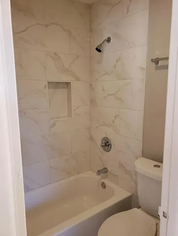 an empty room with wooden floor closet and windows