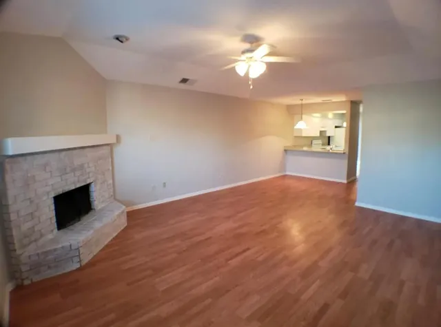 a view of empty room with wooden floor and fireplace