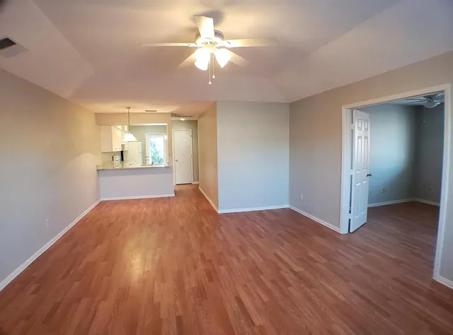 an empty room with wooden floor and windows