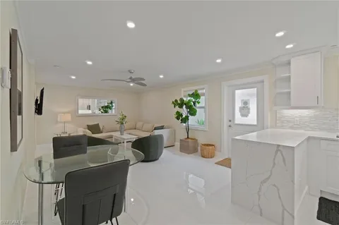 a living room with furniture a potted plant and a kitchen view