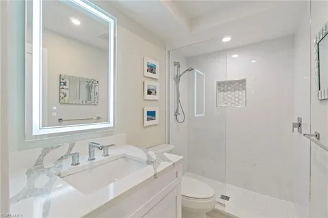 a bathroom with a granite countertop sink a toilet and shower