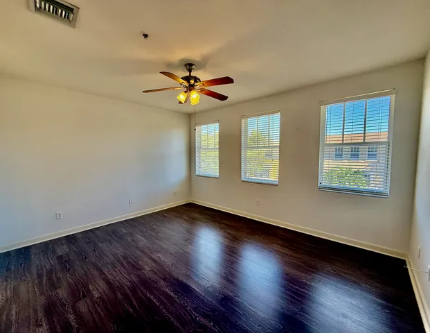 a view of an empty room with window and wooden floor