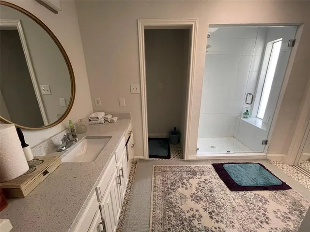 a bathroom with a granite countertop sink a mirror and shower