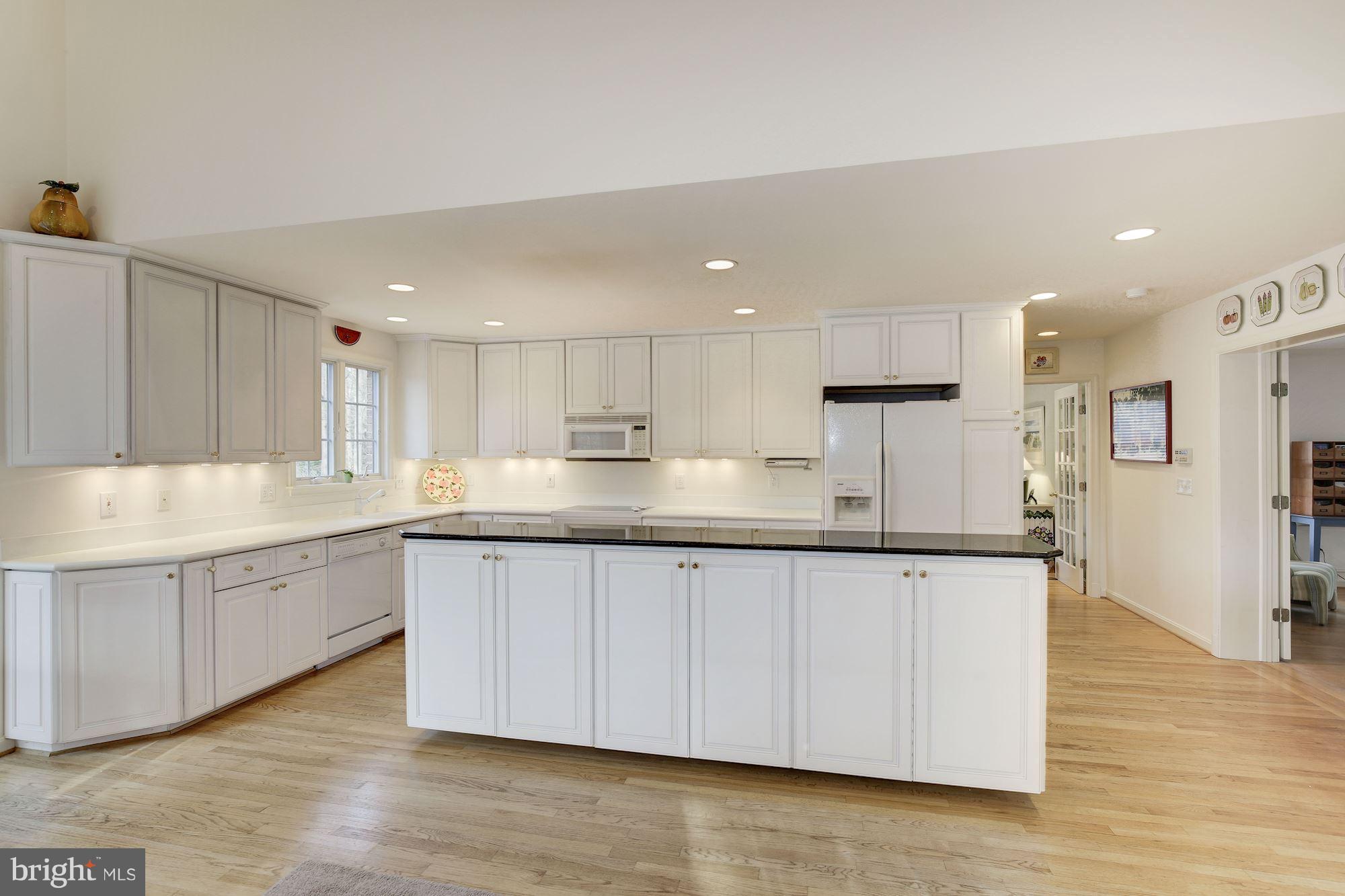 8821 Belmart Road Potomac, MD 20854 - Photo 7 of 29 a large kitchen with granite countertop a white stove top oven and white cabinets