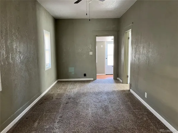 an empty room with a chandelier fan and windows