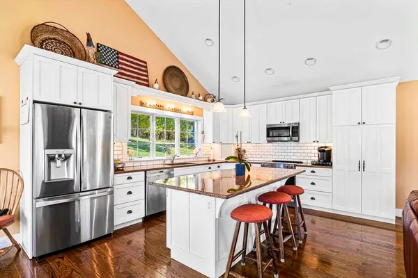 a kitchen with stainless steel appliances a refrigerator a stove a sink and white cabinets with wooden floor