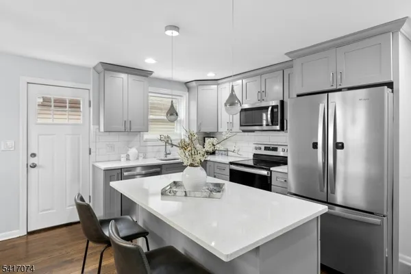 a kitchen with a refrigerator a stove a sink and chairs