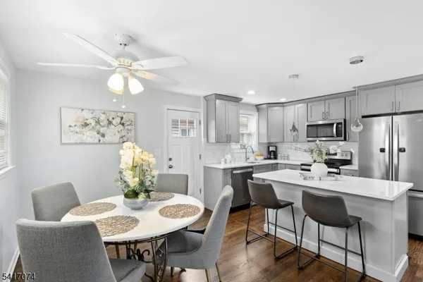 a kitchen with a dining table cabinets appliances and wooden floor