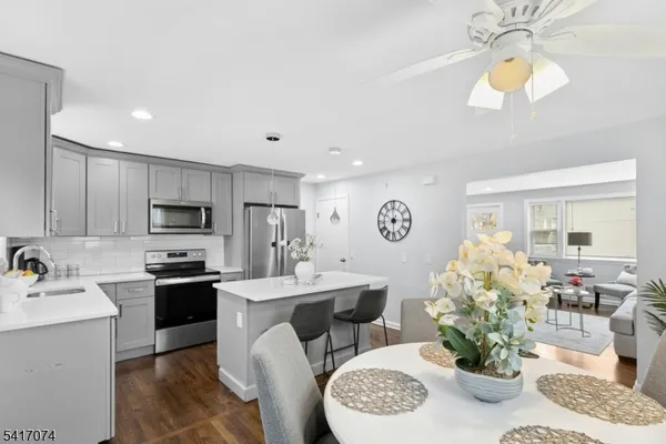 a kitchen with stainless steel appliances kitchen island granite countertop a sink a stove a dining table and chairs