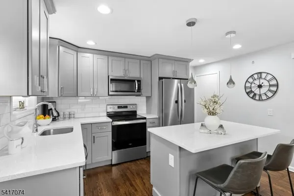 a kitchen with stainless steel appliances a sink a stove a refrigerator cabinets a dining table and chairs