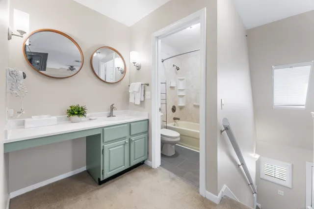 a spacious bathroom with a double vanity sink a mirror and a toilet
