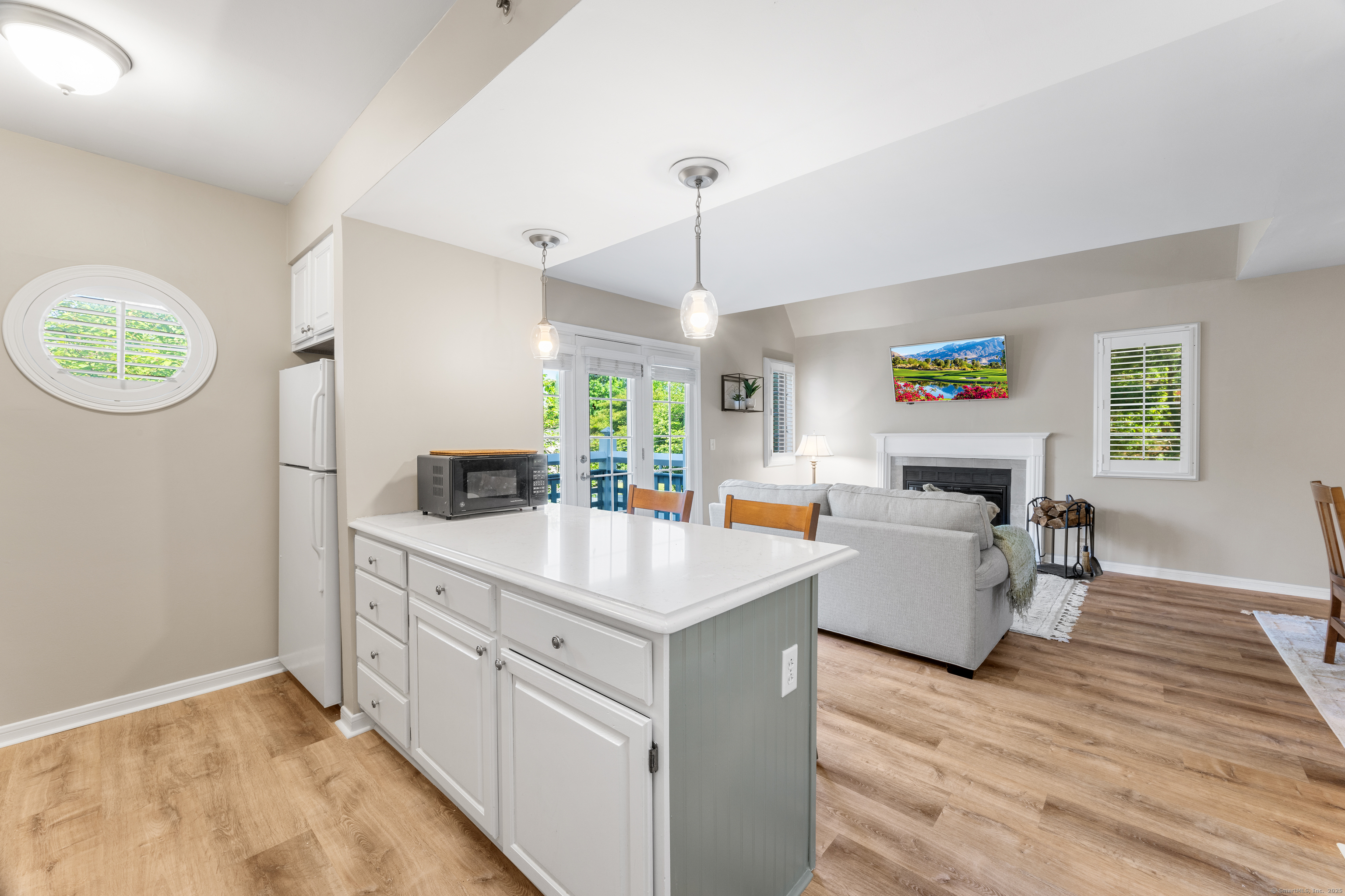 2124 Old Pond Lane, Unit 2124 Norwich, CT 06360 - Photo 3 of 30 a room with kitchen island a wooden floor and a chandelier
