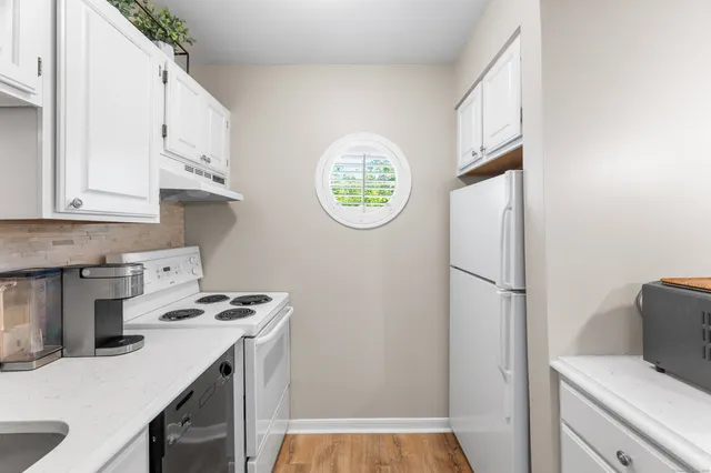 a kitchen with a refrigerator a stove and white cabinets